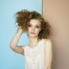 woman leaning on wall holding her hair